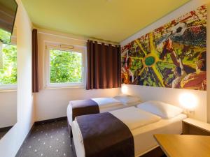 une chambre d'hôtel avec 2 lits et un tableau mural dans l'établissement B&B HOTEL Dortmund-Messe, à Dortmund