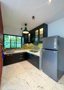 cocina con armarios negros y nevera de acero inoxidable en Cloud9 Villa (Yeoor Hills, Thane) - A Luxurious Private Jungle Villa., en Thane