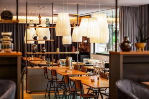 een restaurant met houten tafels en stoelen en kroonluchters bij Vienna House Easy by Wyndham Stuttgart in Stuttgart