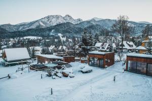 un pueblo cubierto de nieve con montañas en el fondo en Tatra Resort & SPA, en Kościelisko