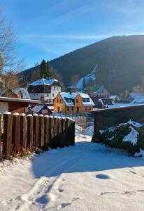 un village enneigé avec une clôture et des maisons dans l'établissement Harrachov 702, à Harrachov