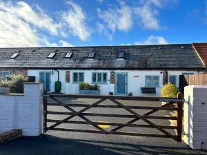 una casa bianca con un cancello in legno davanti di The Dairy, Bramble Farm Cottages a Ferndown