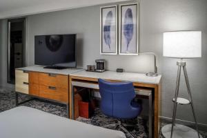 um quarto com uma secretária, uma televisão e uma cadeira azul em DoubleTree by Hilton Hotel Denver em Denver