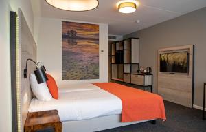 - une chambre avec un grand lit et une couverture orange dans l'établissement Hotel Restaurant Eeserhof, à Ees