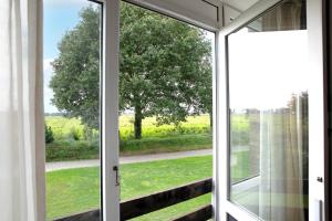 une porte en verre ouverte avec vue sur un champ dans l'établissement Hotel Restaurant Eeserhof, à Ees