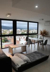 a living room with a table and chairs and a large window at Departamentos Ciudad de Nieva in San Salvador de Jujuy