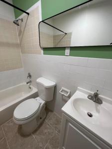 a bathroom with a toilet and a sink and a mirror at East Harlem Hostel in New York