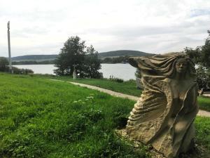 a statue of a woman sitting in the grass near a body of water at BohnApartments Juwel am See, mitten in der Natur - gratis Parkplatz - Kamin - WLAN - Nähe Erfurt in Kranichfeld