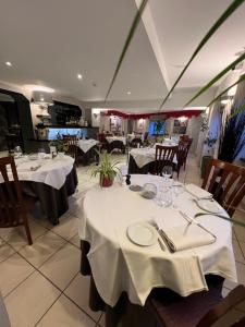 uma sala de jantar com mesas e toalhas de mesa brancas em La glycine hotel et spa em Bénouville