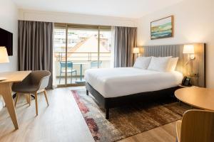 een hotelkamer met een bed, een bureau en een tafel bij Staybridge Suites - Cannes Centre, an IHG Hotel in Cannes