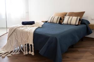 a bed with a blue blanket and pillows on it at VILLA WINE & BEACH Design and Luxury in Cala Crancs in Salou