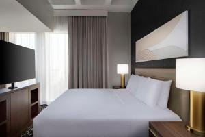 a bedroom with a large white bed and a flat screen tv at Hyatt House LAX Century Blvd in Los Angeles