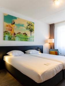 een slaapkamer met een groot bed en een schilderij aan de muur bij Hotel Alkmaar in Alkmaar