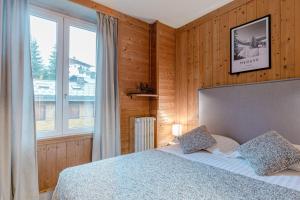 een slaapkamer met een bed en een groot raam bij Le Chalet d'Antoine - Centre de Megève in Megève