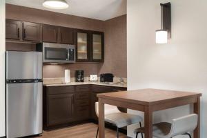 Residence Inn Houston The Woodlands/Market Street في ذا وودلاندس: مطبخ مع طاولة وثلاجة حديد قابلة للصدأ