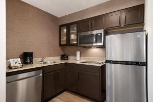 Residence Inn Houston The Woodlands/Market Street في ذا وودلاندس: مطبخ مع دواليب بنية وثلاجة حديد قابلة للصدأ