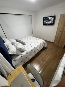 a bedroom with a bed and a tv on a wall at APARTAMENTO PRIVADO cerca al aeropuerto in Bogotá