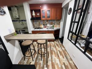 a small kitchen with a wooden counter and stools at APARTAMENTO PRIVADO cerca al aeropuerto in Bogotá