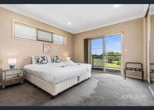 ein Schlafzimmer mit einem großen Bett und einem großen Fenster in der Unterkunft Freestanding house with ocean view in Port Campbell