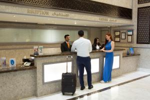 Un uomo e una donna in piedi al bancone della reception di Carlton Tower Hotel a Dubai