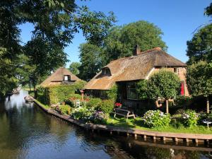 een paar rieten huisjes naast een kanaal bij Plompeblad Suite Giethoorn in Giethoorn