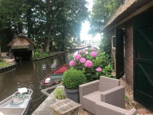 een balkon met bloemen en een boot op een kanaal bij Plompeblad Suite Giethoorn in Giethoorn