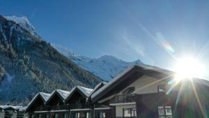 um edifício em frente a uma montanha com o sol em Plan B Hotel - Living Chamonix em Chamonix-Mont-Blanc