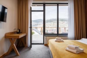 Cette chambre comprend un lit, un bureau et une fenêtre. dans l'établissement Yo Hotel, à Bukovel