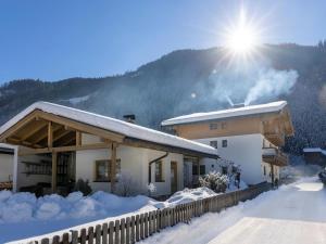 um edifício coberto de neve com o sol atrás dele em apartment Eva in Wald im Pinzgau with balcony em Wald im Pinzgau