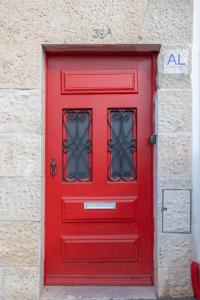 une porte rouge avec fenêtre dans un bâtiment dans l'établissement Casas da Couraça, à Coimbra