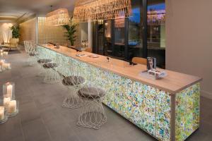 a restaurant with a colorful counter with stools at ME Sitges Terramar in Sitges