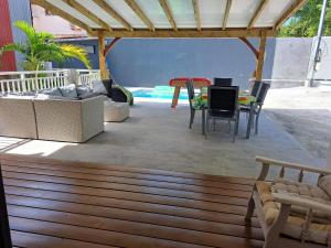 een terras met een tafel en stoelen bij Chambres d'hôtes dans Villa à Chateauboeuf in Fort-de-France