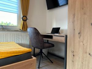 a bedroom with a desk with a laptop and a bed at Gästehaus Trockau in Pegnitz