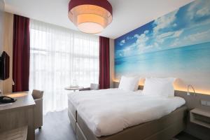 una camera da letto con un grande letto e un dipinto sul muro di Ramada The Hague Scheveningen a Scheveningen