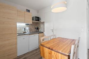 a kitchen with a wooden table and white cabinets at Smartstay Altineige - Val Thorens in Val Thorens