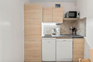 a small kitchen with white appliances and wooden cabinets at Smartstay Altineige - Val Thorens in Val Thorens