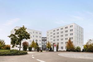 deux bâtiments blancs avec une route devant elle dans l'établissement Vienna House Easy by Wyndham Neckarsulm, à Neckarsulm