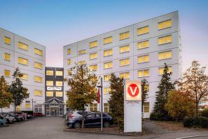 un bâtiment blanc avec un panneau devant lui dans l'établissement Vienna House Easy by Wyndham Neckarsulm, à Neckarsulm