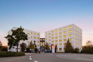 2 bâtiments blancs avec une rue en face dans l'établissement Vienna House Easy by Wyndham Neckarsulm, à Neckarsulm