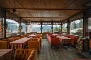 un restaurant avec des tables, des chaises et des montagnes en arrière-plan dans l'établissement Korunka, à Tatariv