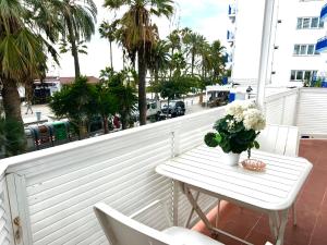 une table blanche avec un vase de fleurs sur un balcon dans l'établissement Sitges Seafront Ribera Apartment, à Sitges