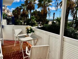 d'un balcon avec une table, des chaises et des palmiers. dans l'établissement Sitges Seafront Ribera Apartment, à Sitges