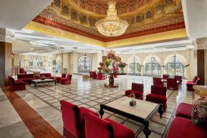 una grande hall con sedie rosse e lampadario a braccio di Fes Marriott Hotel Jnan Palace a Fes