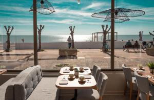 - un restaurant avec des tables et des chaises et une vue sur la plage dans l'établissement Hôtel Le Rivage vue sur mer - Châtelaillon-plage, à Châtelaillon-Plage