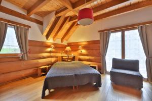 a bedroom with a bed and a chair at Chambres d'hôtes Les Rondins De La Fecht in Mittlach