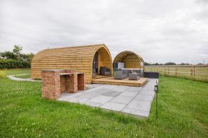 ein Holzgebäude mit zwei Bögen auf einem Grasfeld in der Unterkunft Little Meadow Pods with Hot Tub in York