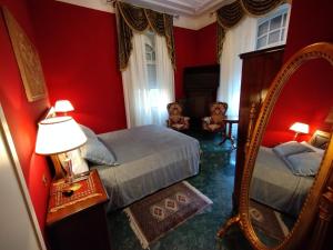 - une chambre rouge avec un lit et un miroir dans l'établissement NOBILI LIBARDI - VILLA BASEVI, à Vérone