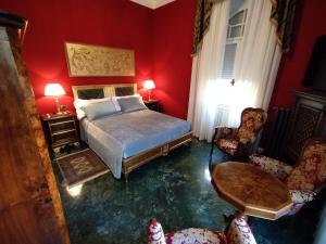 - une chambre avec des murs rouges, un lit et deux chaises dans l'établissement NOBILI LIBARDI - VILLA BASEVI, à Vérone