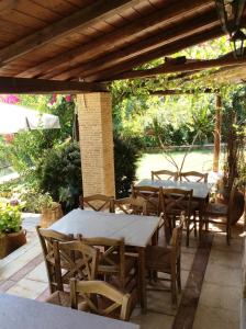 een patio met tafels en stoelen onder een houten pergola bij Angelica Villas Hotel Apartments in Oud Epidauros