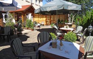 eine Terrasse mit Tischen, Stühlen und einem Sonnenschirm in der Unterkunft Weißer Stein Jonsdorf in Kurort Jonsdorf